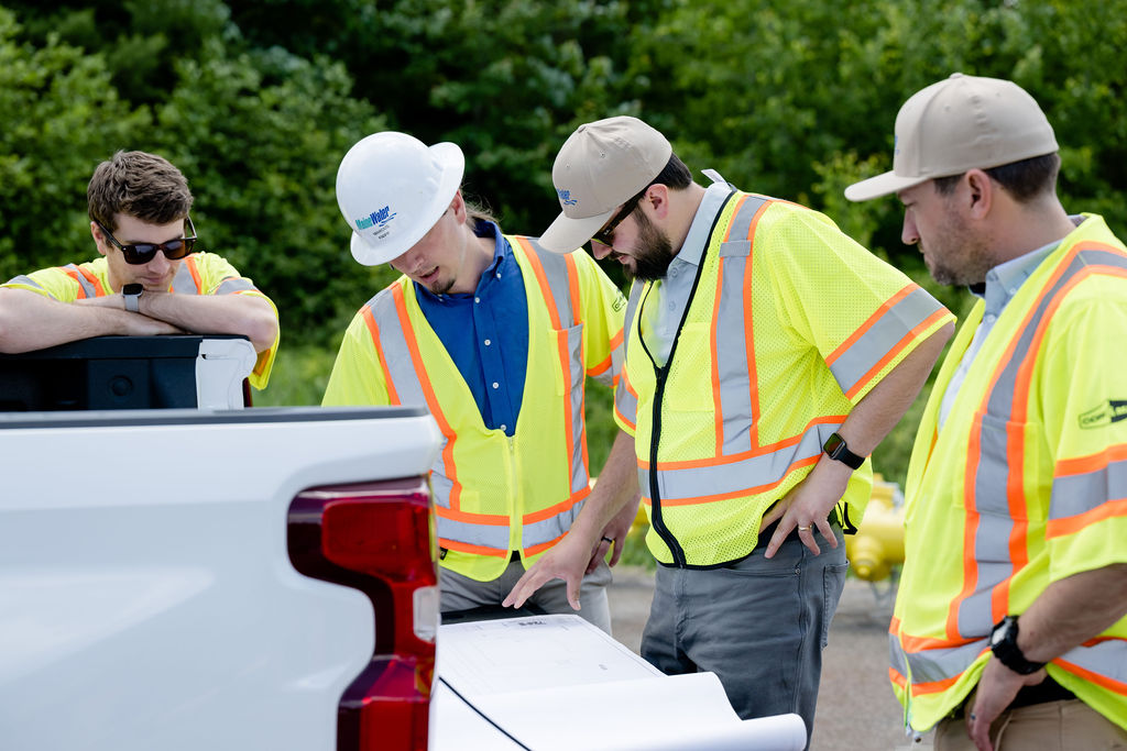 people on the job site in saftey vets and hard hats looking at project plans